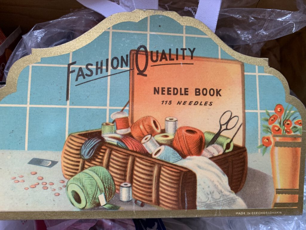 Fashion Quality Needle book - en illustration med sytrådar och sax.